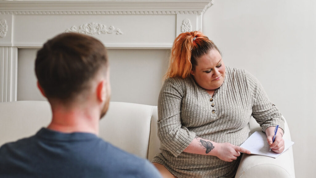 A therapist providing counseling for anxiety disorder to a client and taking notes during the session.